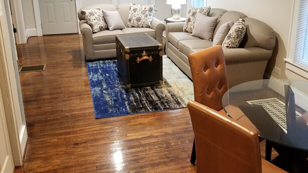 A living room with a brown leather chair, a glass coffee table, a beige sofa, and a patterned rug. - The Blackberry Inn Guest House (Watkins Glen)