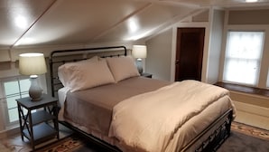 A bedroom with a bed, two bedside tables with lamps, a window with blinds, and a door. - The Blackberry Inn Guest House (Watkins Glen)