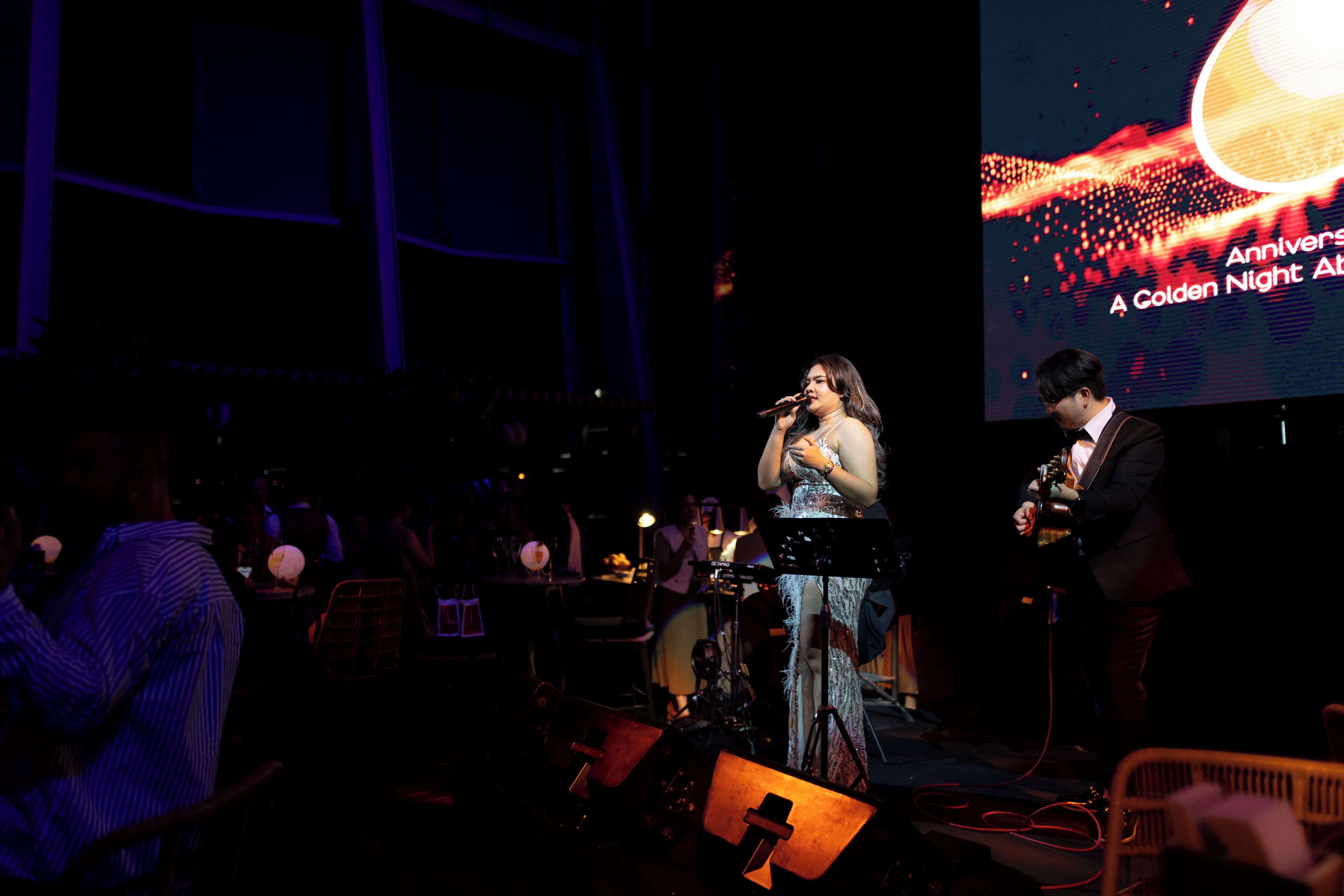 A stage with a performer and a screen displaying "Anniversary A Golden Night".