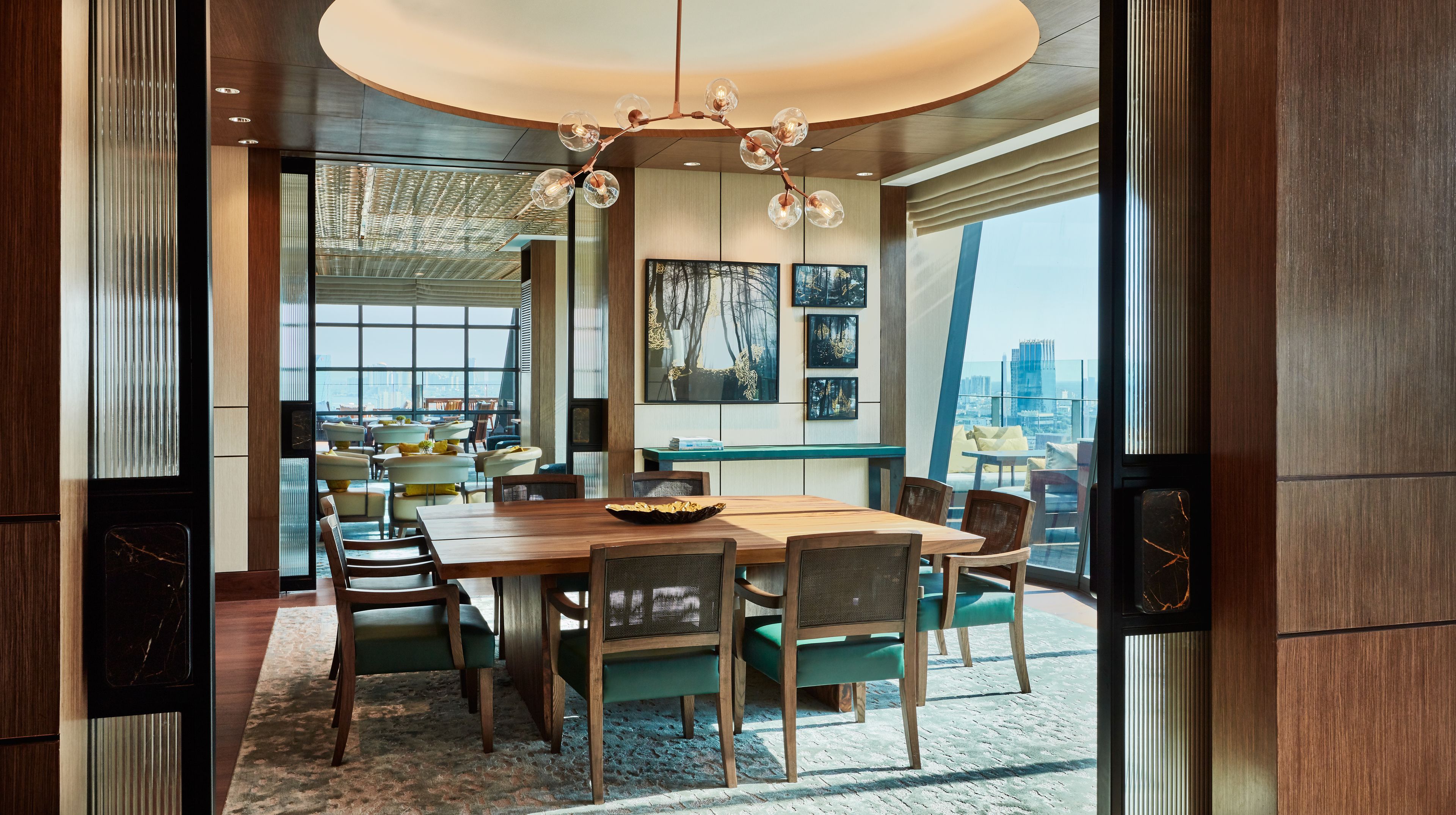 A modern dining area with a wooden table, chairs, and a chandelier.