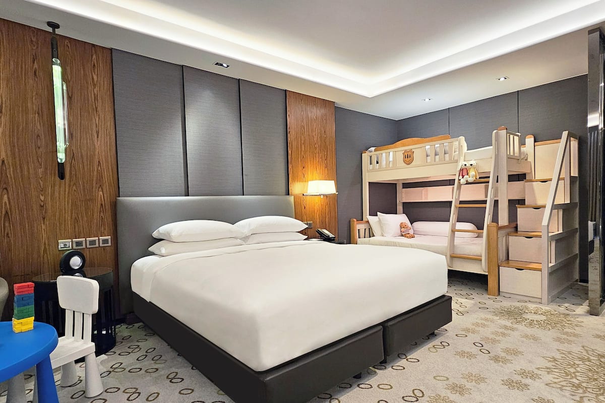 Une chambre d’hôtel moderne équipée d’un grand lit, d’un lit superposé, d’un bureau et d’une chaise.