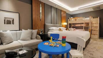 Une chambre d’hôtel avec un lit, un canapé, une petite table avec des jouets et un lit superposé.