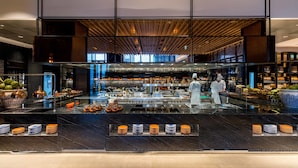 A modern kitchen with a glass counter, stainless steel appliances, and a chef preparing food. - Hyatt Regency Bangkok Sukhumvit (Bangkok)