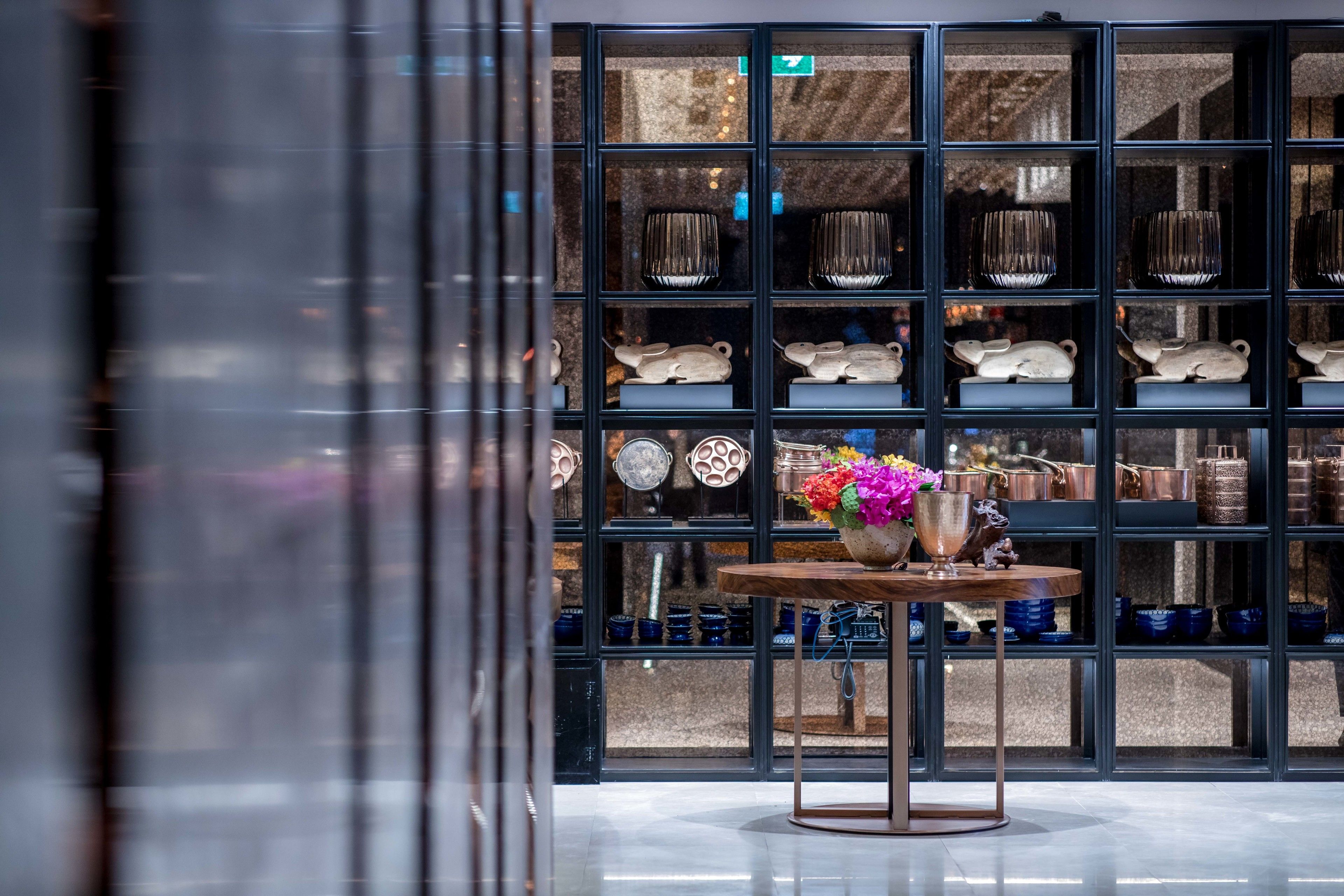 A modern interior with a display of ceramic dishes and a table with a vase of flowers.