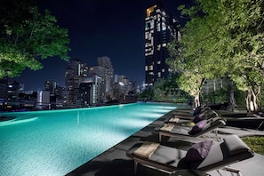 A rooftop pool with lounge chairs and a city skyline in the background. - Hyatt Regency Bangkok Sukhumvit (Bangkok)