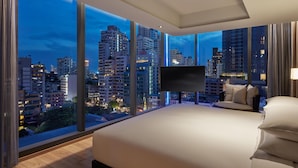 Une chambre d’hôtel moderne dotée d’un grand lit, d’une télévision à écran plat et offrant une vue sur la ville.
