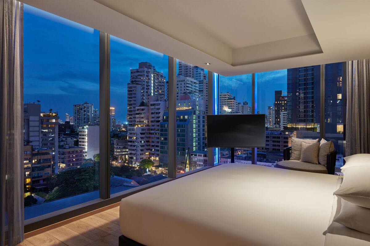 Une chambre d’hôtel moderne dotée d’un grand lit, d’une télévision à écran plat et offrant une vue sur la ville.