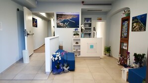 A reception area with a desk, a blue counter, and a wall-mounted display. - Bike&Boat Argentario Hotel (Monte Argentario)