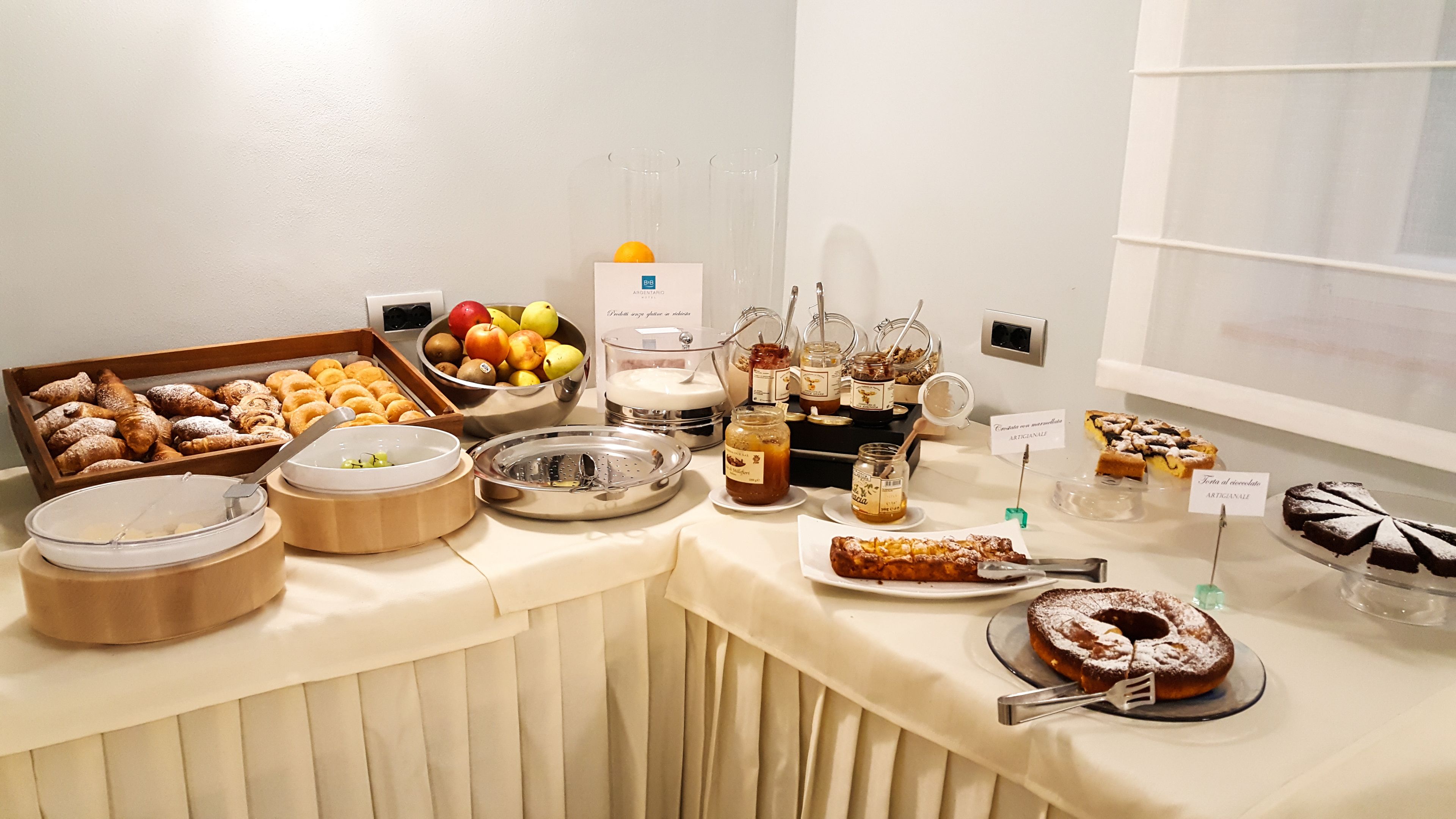 Une table de buffet proposant une variété d’aliments, notamment des pâtisseries, des fruits et des desserts.