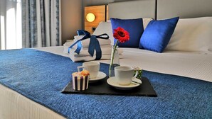 A hotel room with a neatly made bed, a coffee table with a flower vase and pastries, and a painting on the wall. - Bike&Boat Argentario Hotel (Monte Argentario)