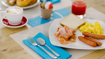 Un plato de desayuno con tocino, salchichas, huevos, tostadas y una taza de café.