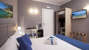 Habitació d'hotel amb llit, escriptori, cadira, armari i televisió.