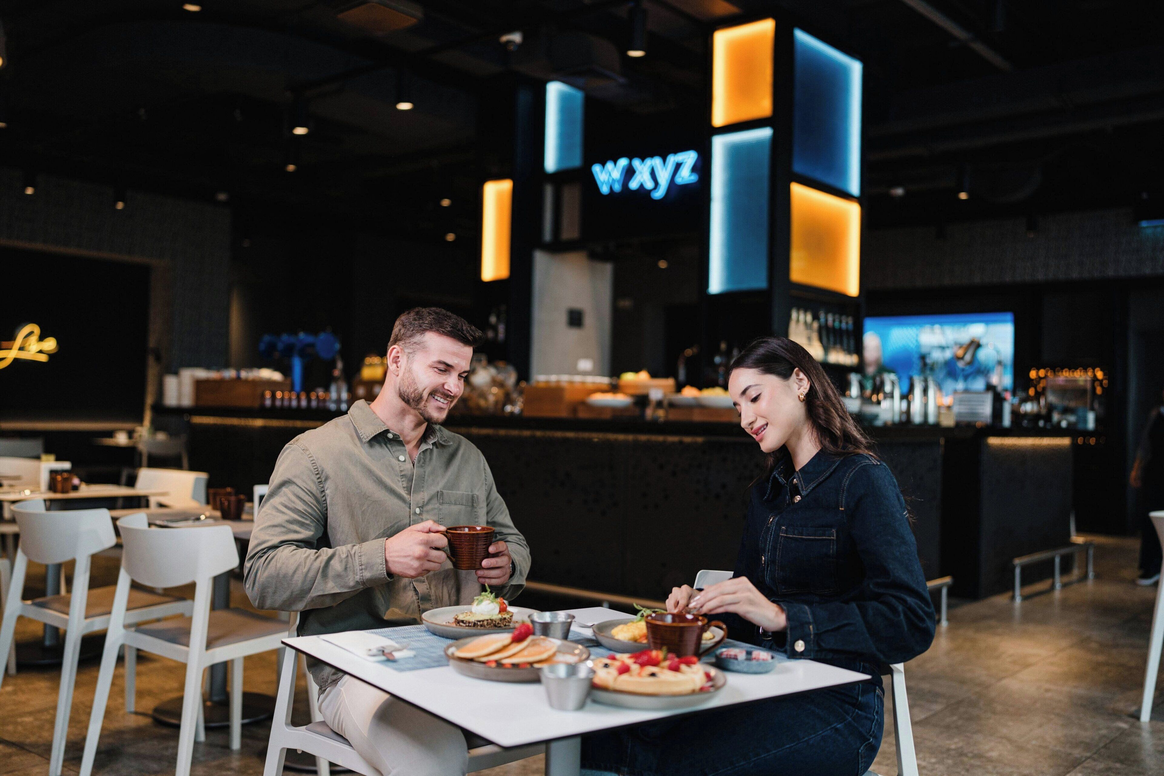 A restaurant with a modern interior, a bar area, and a neon sign.