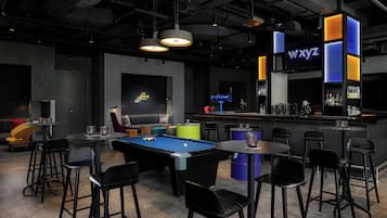 Zona de bar con mesa de billar, taburetes y un letrero de neón que dice "wxyz".