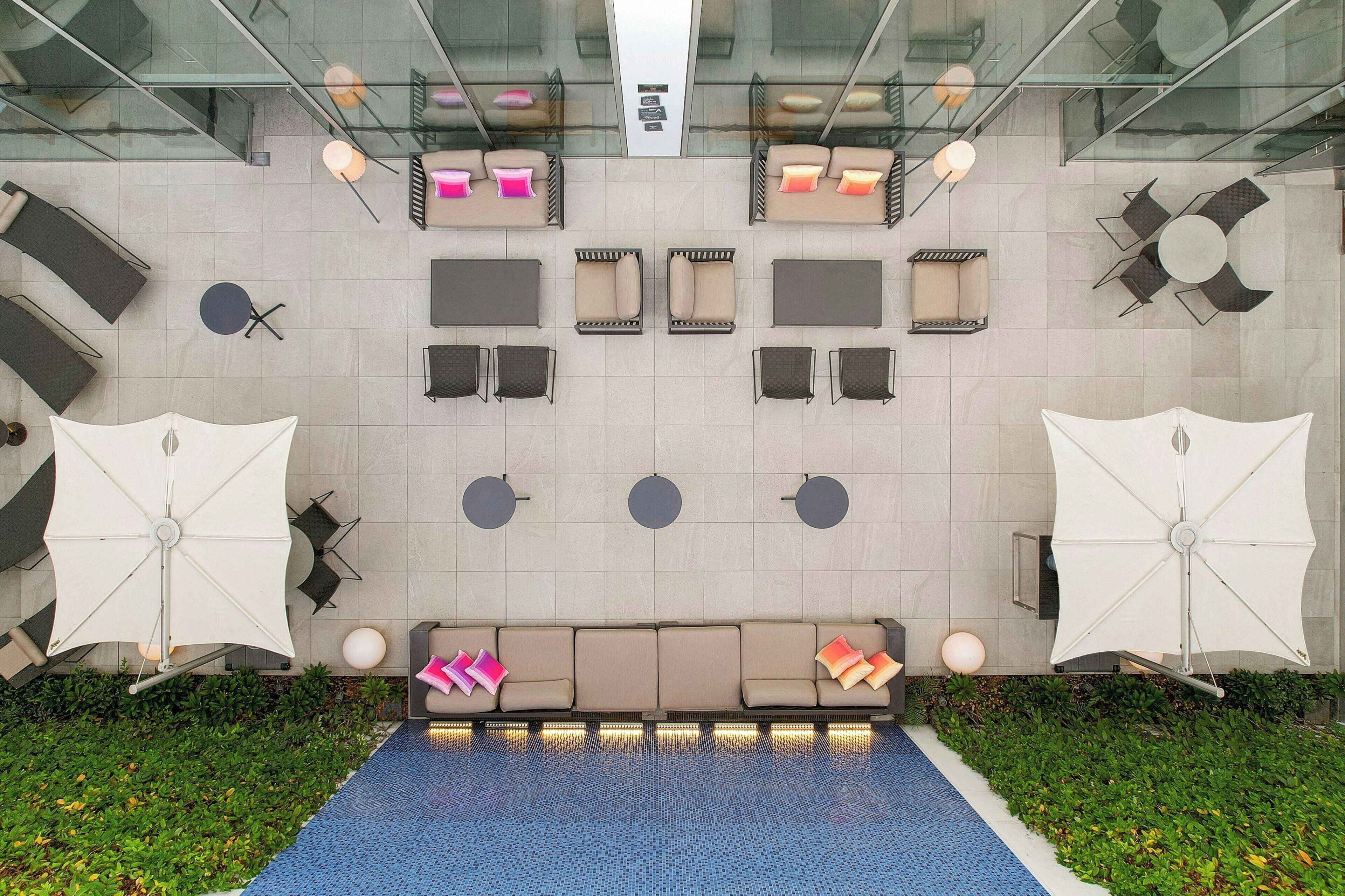 A rooftop lounge area with multiple seating options, including sofas and chairs, arranged around a central water feature.