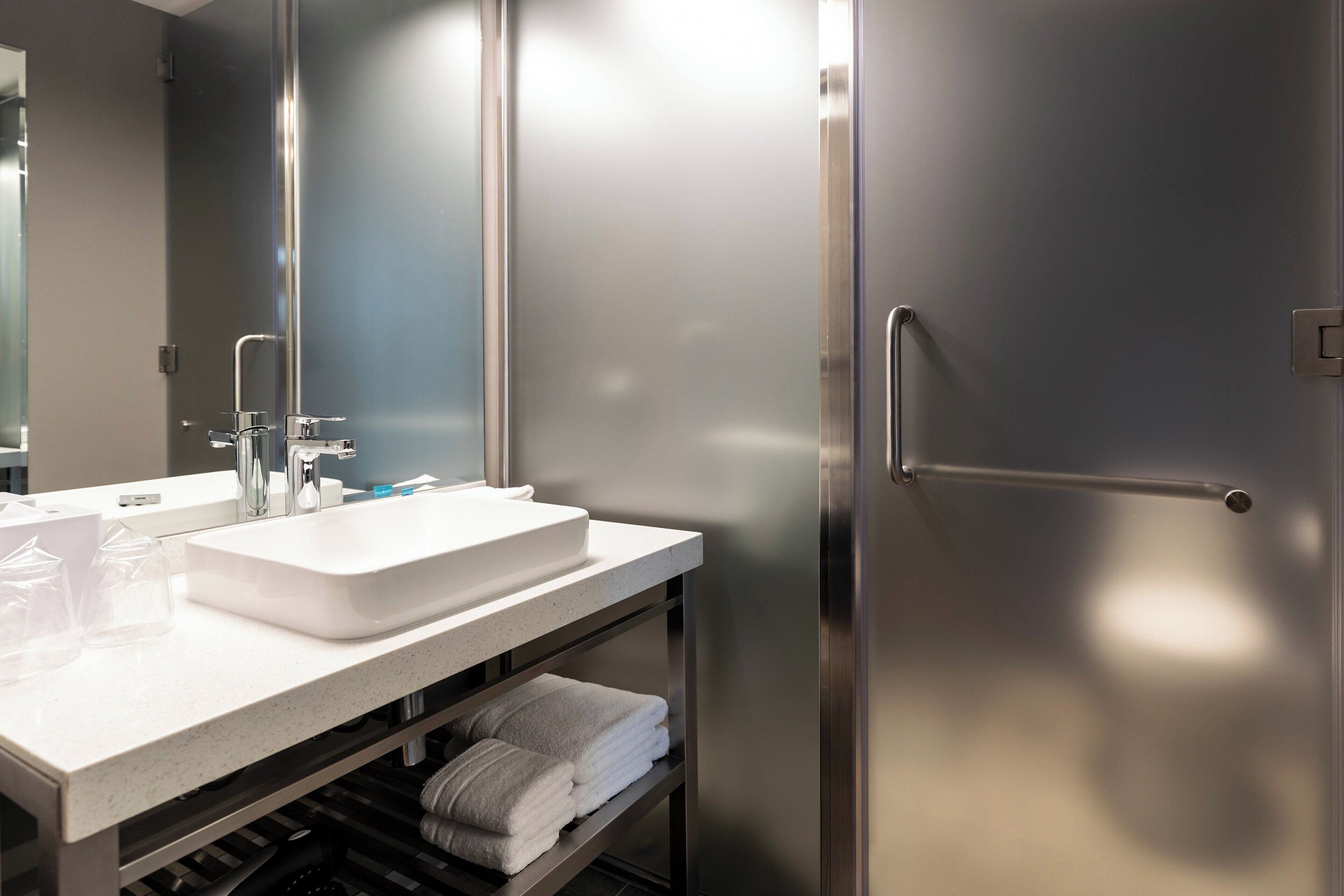 A modern bathroom with a white sink, stainless steel fixtures, and a towel rack.