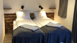 A double bed with a wooden headboard, two bedside tables, and a wall-mounted lamp. - Hrafnavellir Guest House (Höfn)