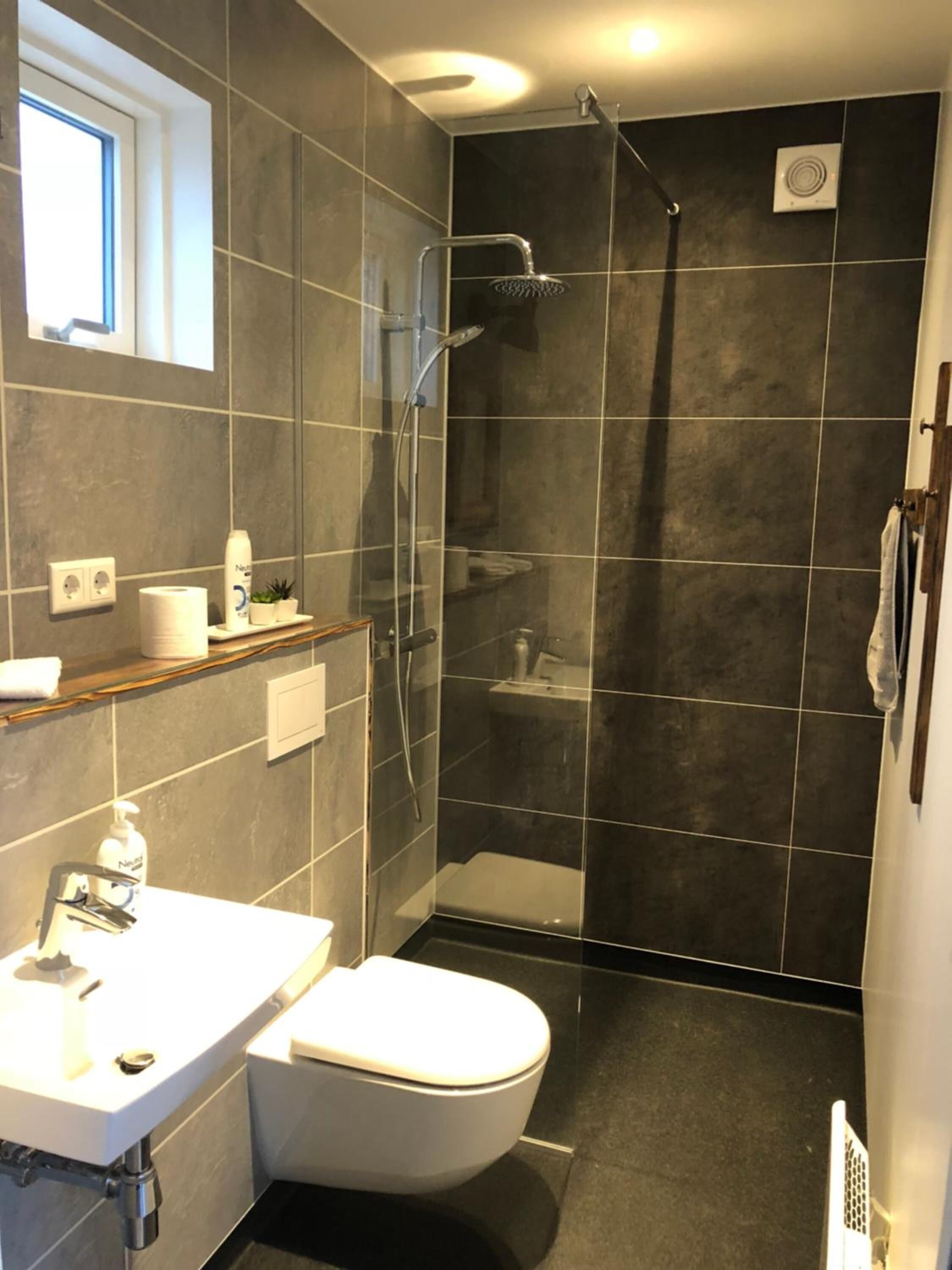 A modern bathroom with a shower, toilet, and sink.