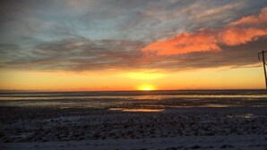 A sunset over a beach with a clear sky and power lines in the foreground. - Hrafnavellir Guest House (Höfn)