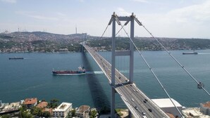 A large suspension bridge spanning a wide body of water with multiple lanes for vehicles and a ship in the foreground. - Sahrakent Otel Atasehir (Istanbul)