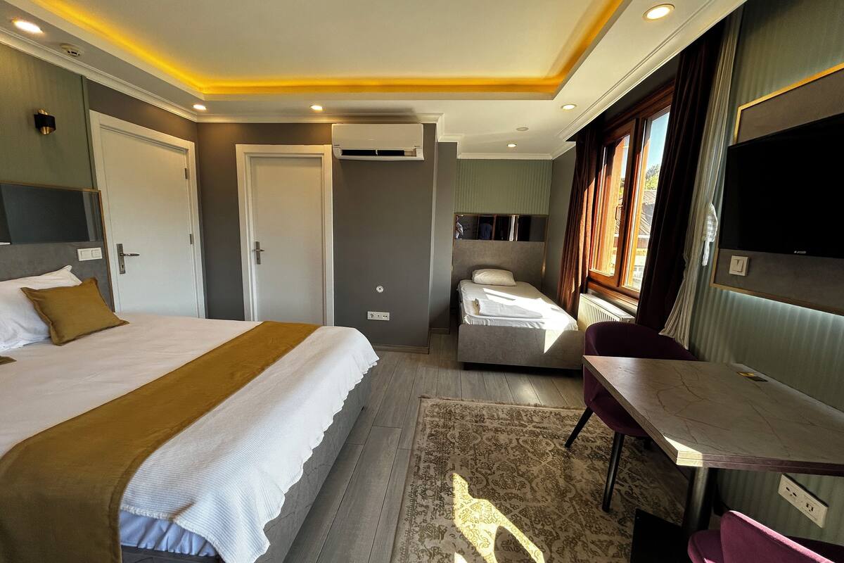 A hotel room with a large bed, a smaller bed, a desk, and a TV.