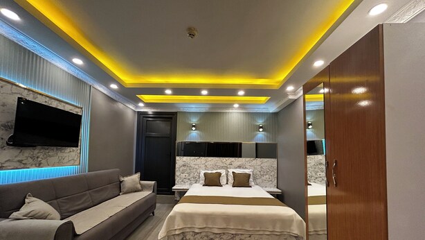 A modern bedroom with a sofa, a bed, and a wardrobe. - Sahrakent Otel Atasehir (Istanbul)