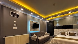 A modern bedroom with a sofa, a bed, a television, and a mirror. - Sahrakent Otel Atasehir (Istanbul)