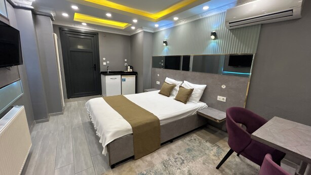 A modern hotel room with a bed, bedside table, chair, and a small kitchenette. - Sahrakent Otel Atasehir (Istanbul)