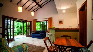 A spacious living area with a sofa, a wooden table, and a blue couch. - Residence Solemare Buzios (Búzios)