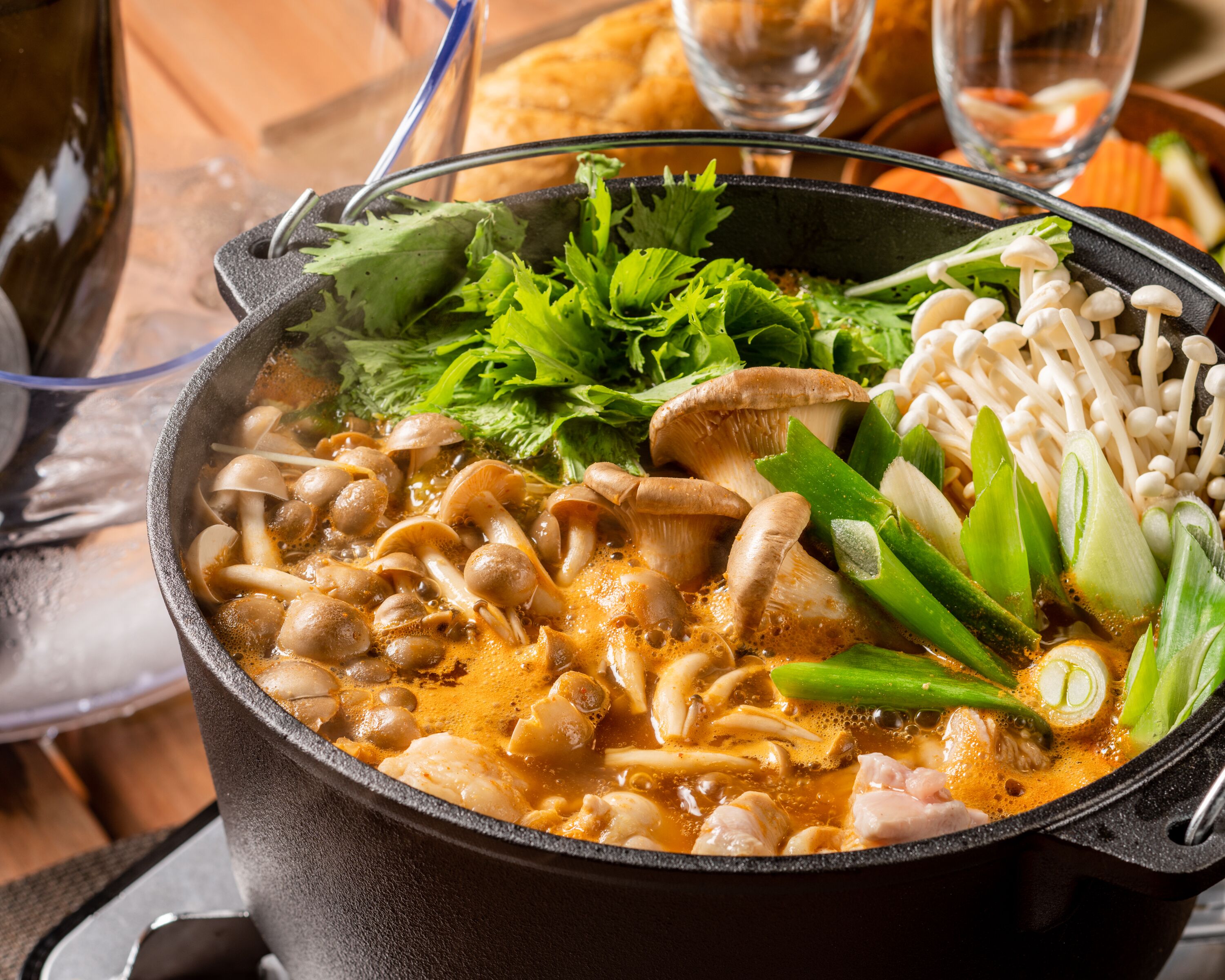 A hot pot with various ingredients like mushrooms, vegetables, and tofu.