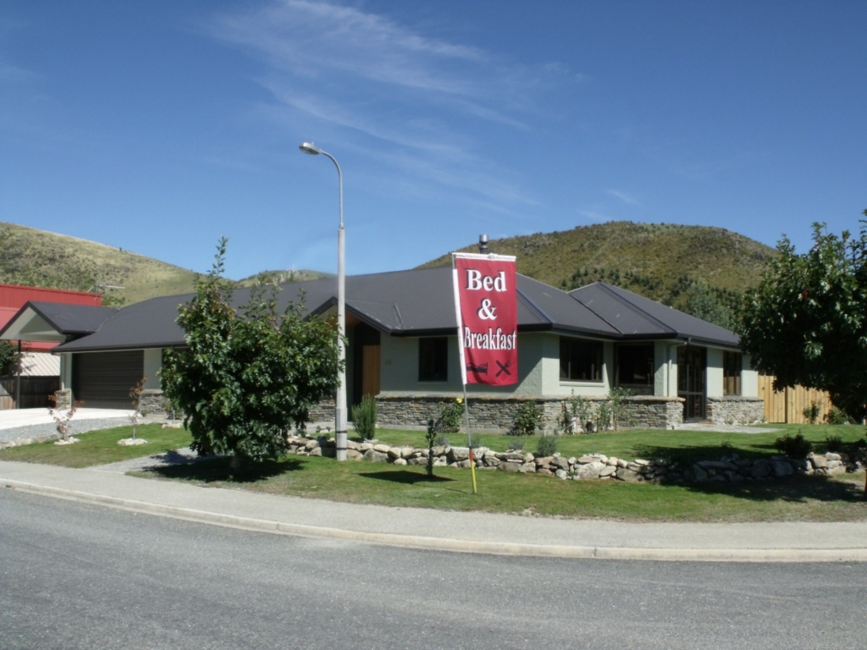 A Bed & Breakfast with a stone facade, a red roof, and a signboard.