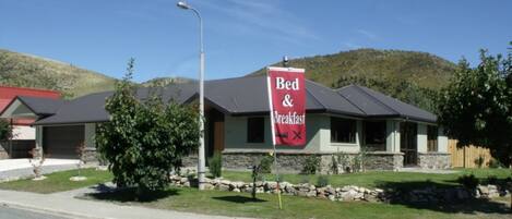 A Bed & Breakfast with a stone facade, a red roof, and a signboard.