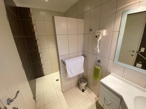 A bathroom with a white sink, a mirror, a towel rack with a white towel, a green towel, and a hairdryer. - BigSky Bed and Breakfast (Omarama)