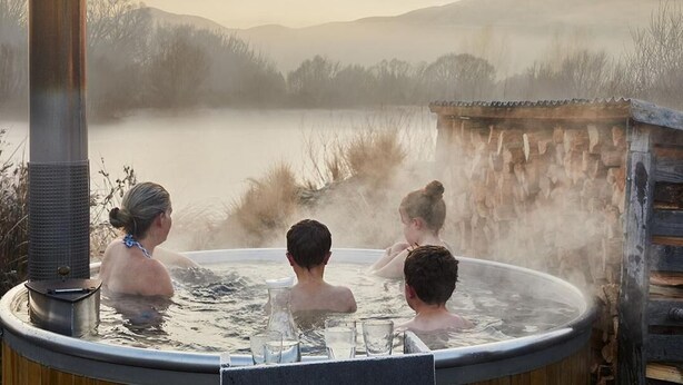 A hot tub with a rustic wooden structure, surrounded by a misty landscape and mountains. - BigSky Bed and Breakfast (Omarama)