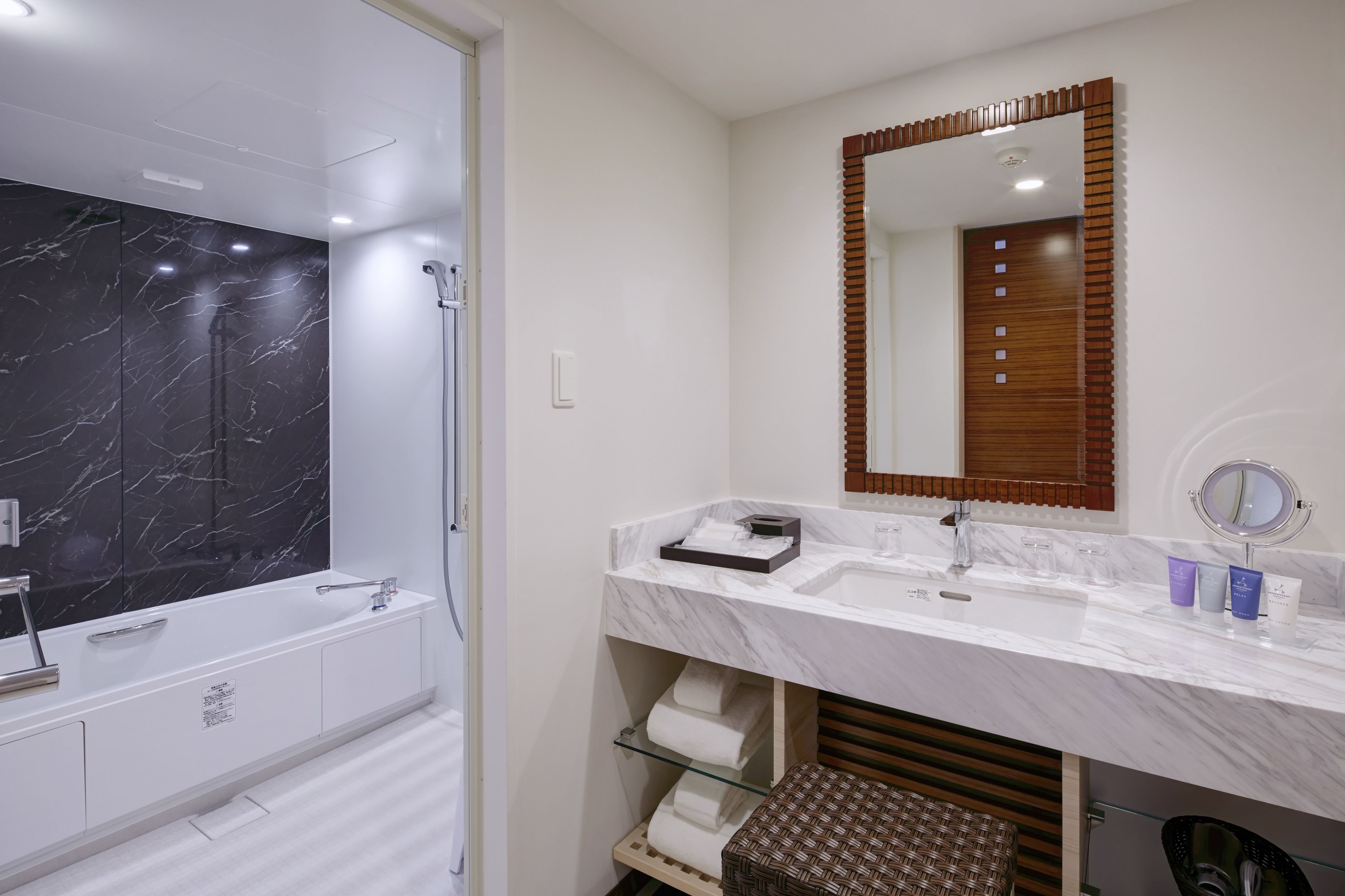 A modern bathroom with a marble shower, a large mirror, and a vanity with a sink and towel rack.