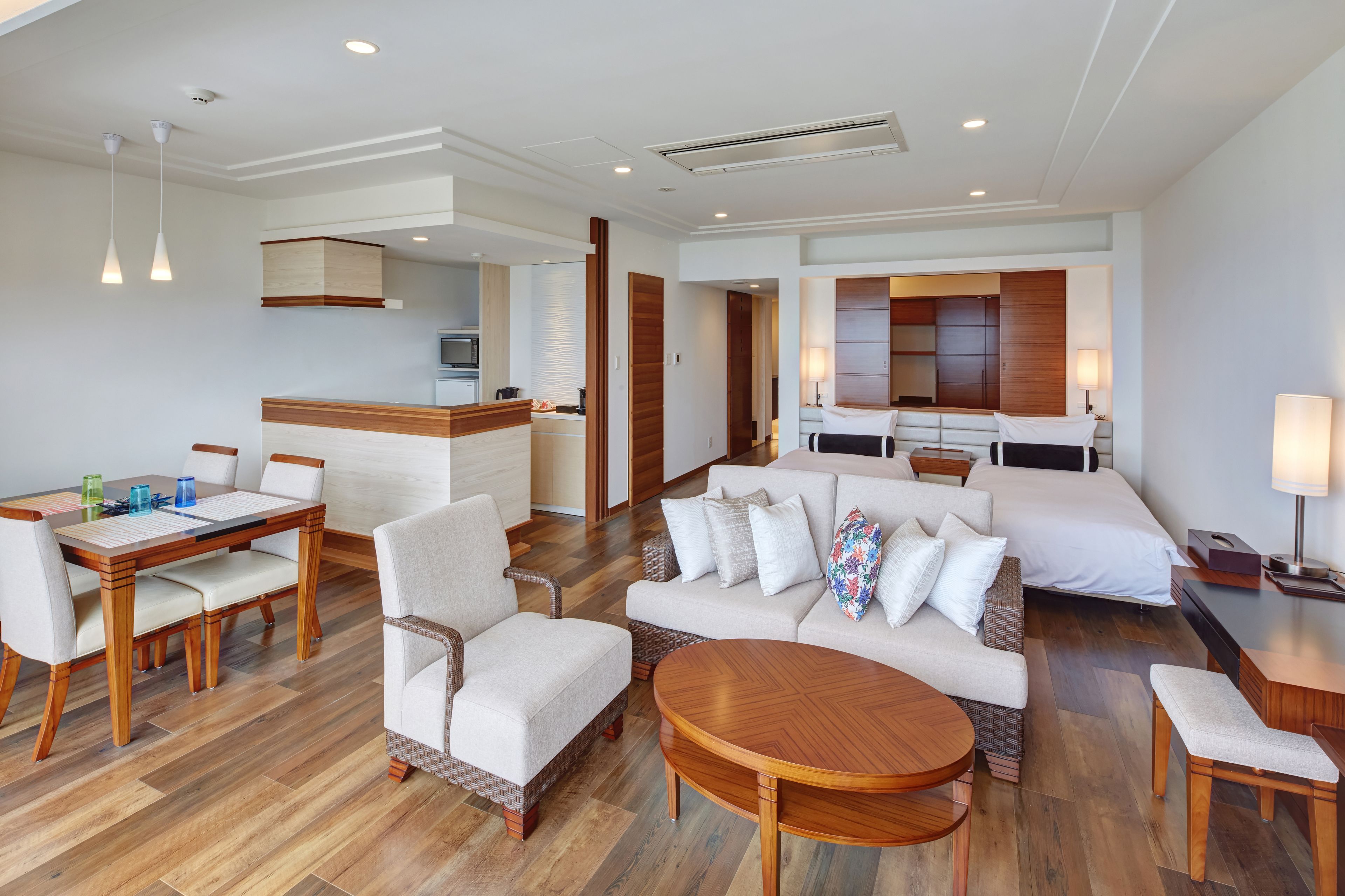 Una habitación de hotel con comedor, un conjunto de sofás, una cama y una kitchenette.