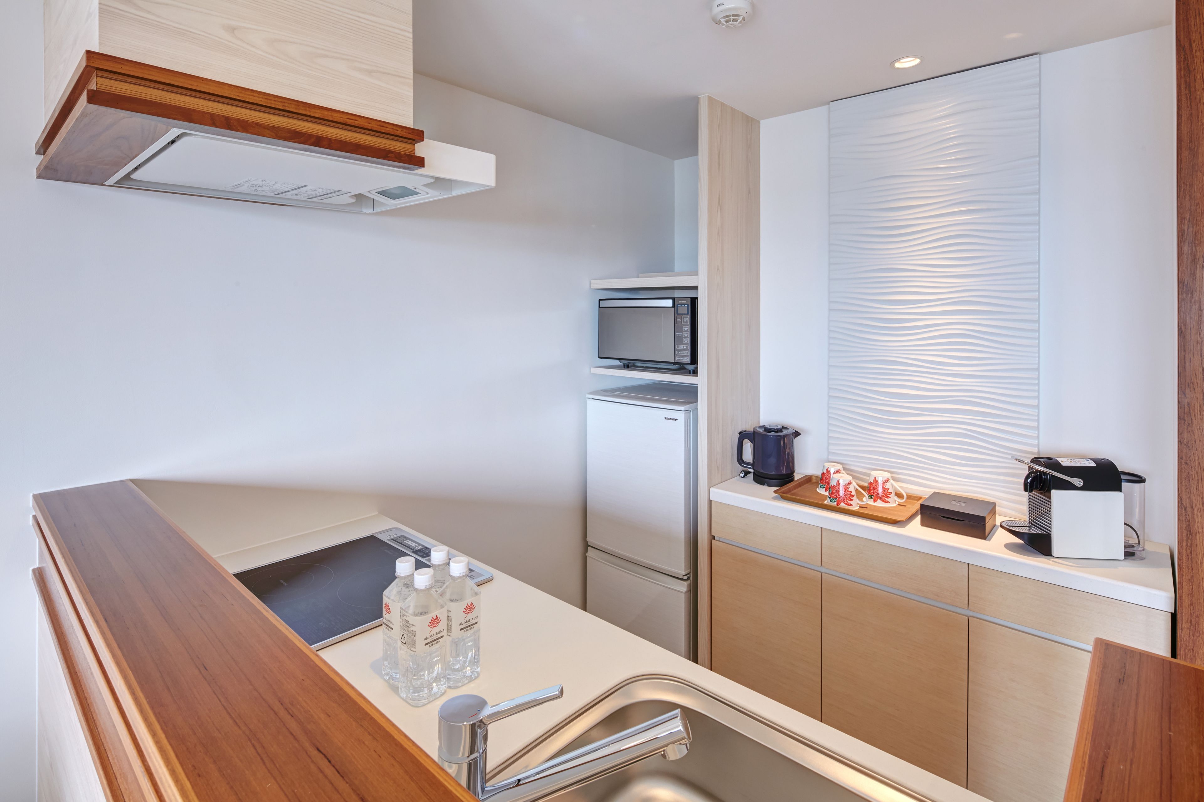 A modern kitchen with a built-in microwave, a coffee maker, and a kettle on the countertop.