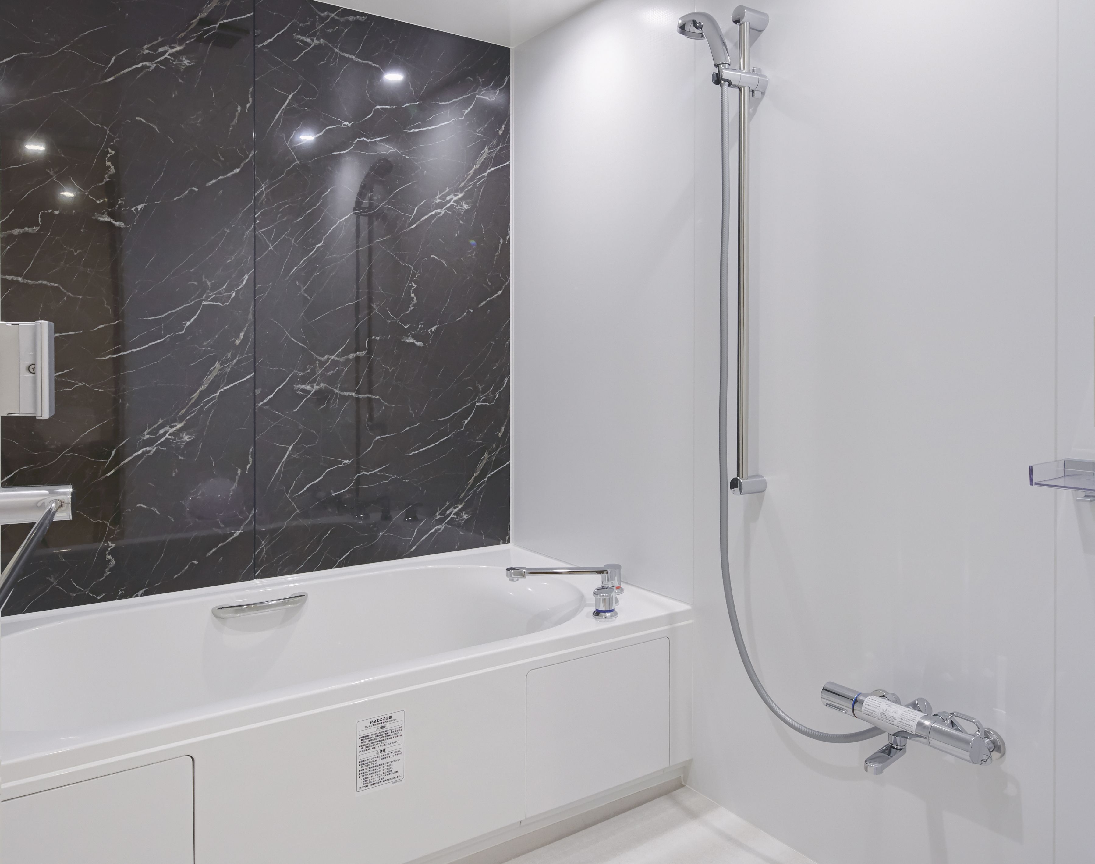 Un baño moderno con tocador de mármol, ducha con cabezal de ducha manual y grifo empotrado.