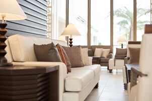 Una sala de estar moderna con un sofá, sillones y lámparas.