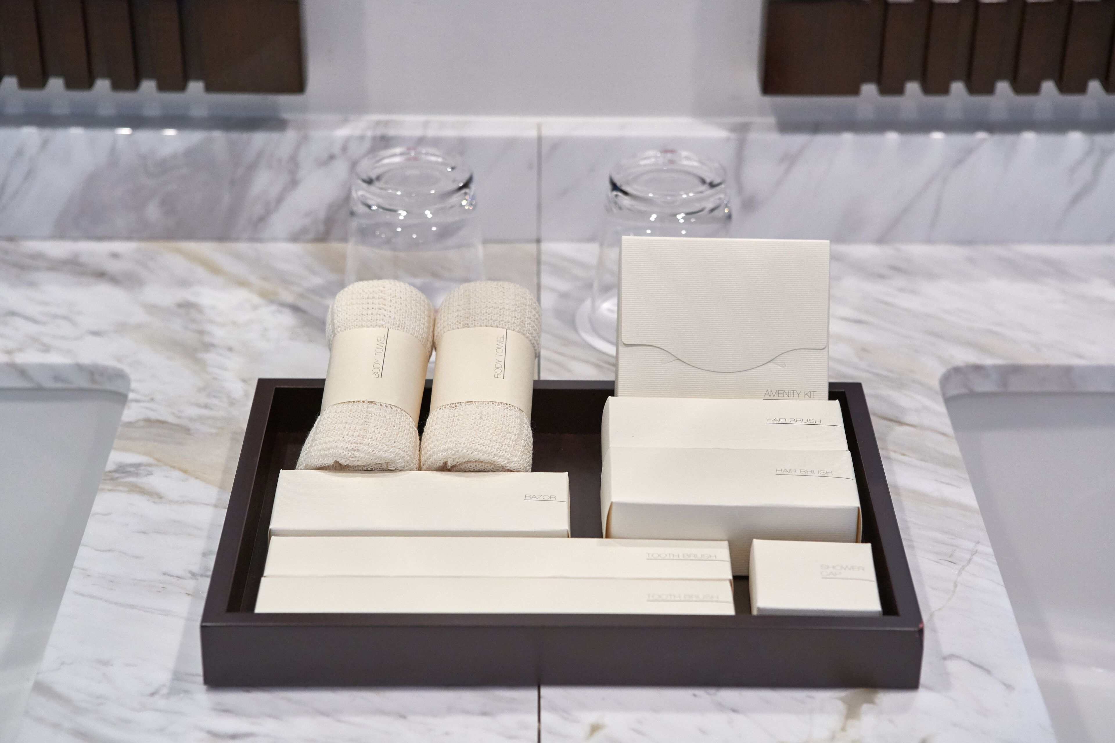 A tray with various toiletries and a razor set on a marble surface.