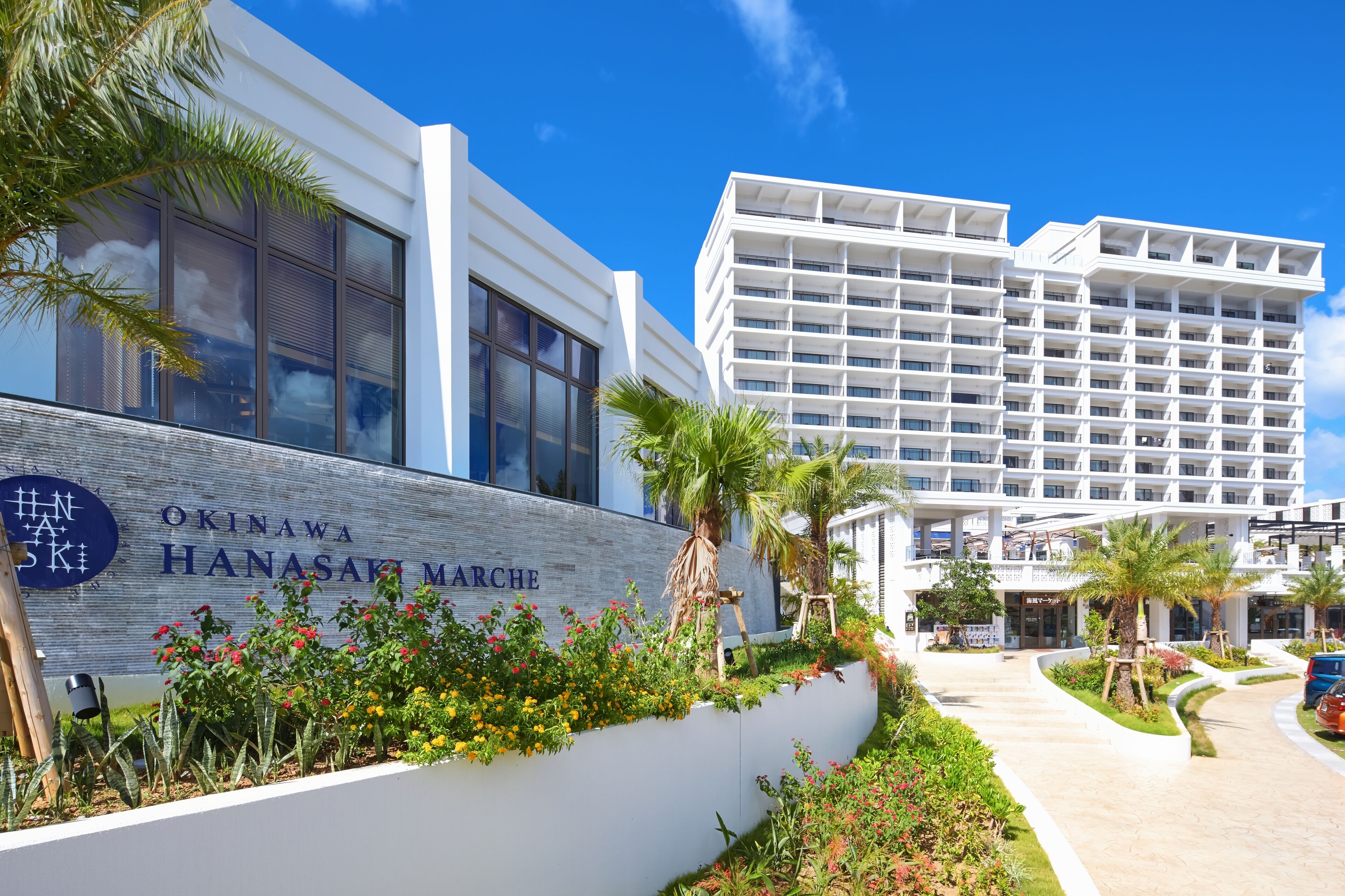 A modern hotel with a sign reading "Okinawa Hanasaki Marche".