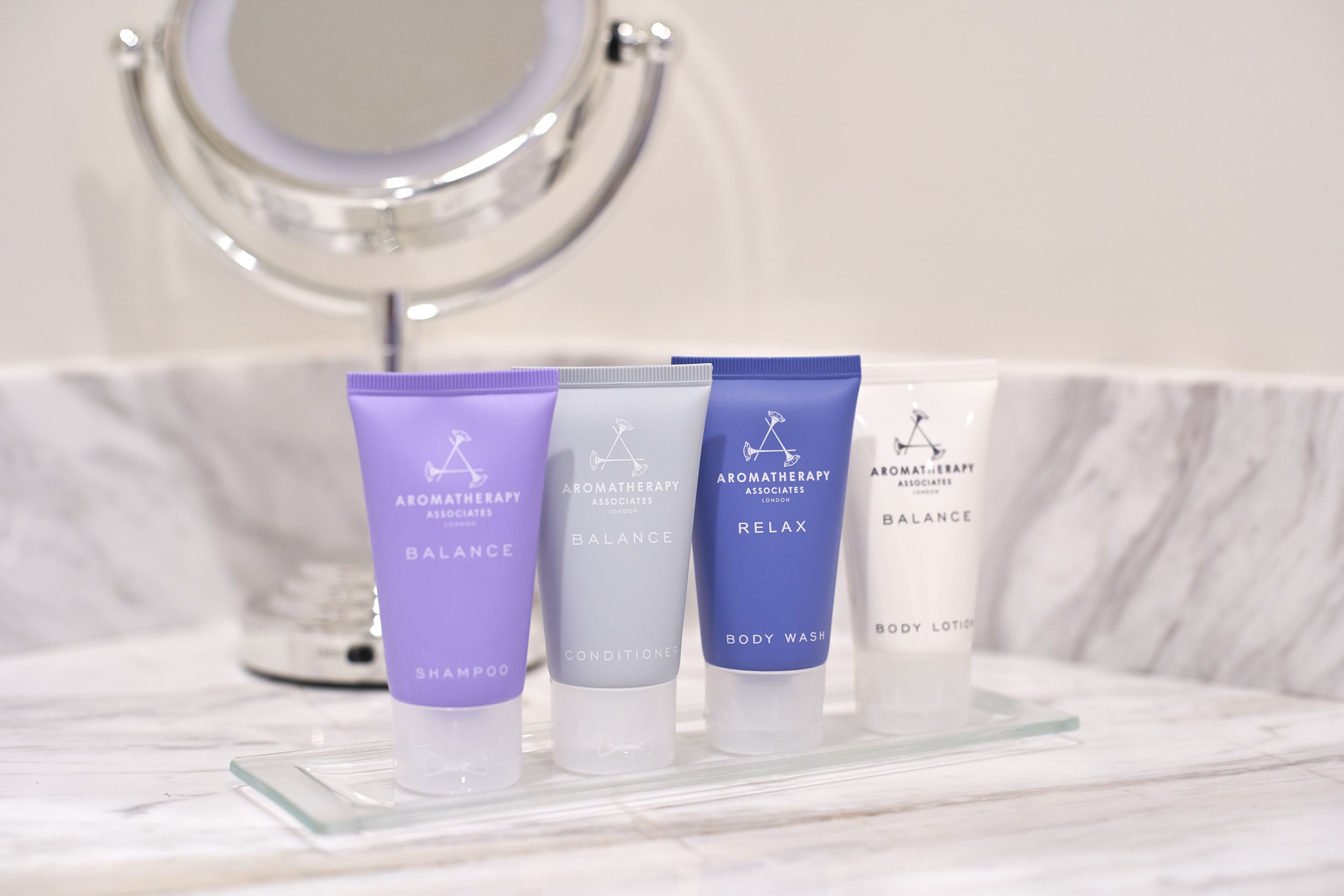 A bathroom vanity with a mirror, a marble countertop, and four bottles of aromatherapy products labeled 'BALANCE'.