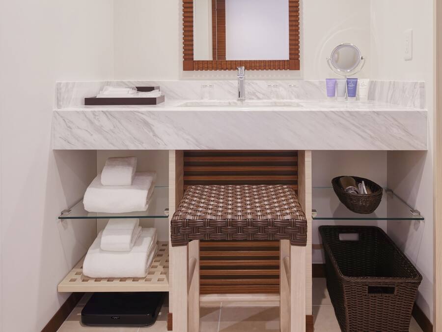 A bathroom with a marble sink, a mirror, a towel rack, and a wicker basket.
