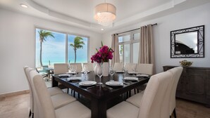 Comedor con una mesa de madera oscura dispuesta para seis personas, rodeada de seis sillas color beige.