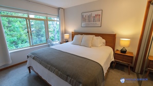 A neatly made bed with a wooden headboard, two bedside lamps, and a framed picture on the wall. - Central, Whistler Village Family Condo. Pool & Hot Tub, Free Parking & WiFi (Whistler)