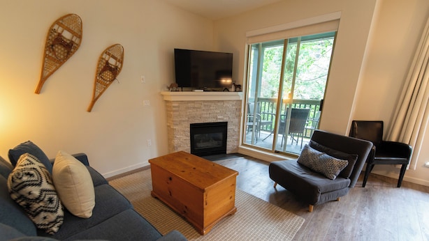A living room with a fireplace, a sofa, a coffee table, and a TV. - Central, Whistler Village Family Condo. Pool & Hot Tub, Free Parking & WiFi (Whistler)