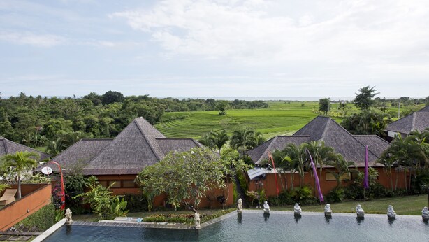 A resort with multiple villas, a swimming pool, and a view of the surrounding green landscape. - 3 Bedroom Sawah Town House B4 Ocean View   (Tabanan)