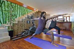Um estúdio de yoga com piso de madeira, equipamentos de exercício e uma escada com design de parede em bambu.