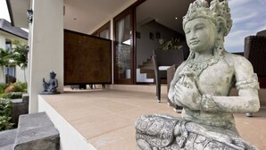 A statue of a seated figure with intricate patterns, positioned on a stone platform in an outdoor setting. - 3 Bedroom Sawah Town House B4 Ocean View   (Tabanan)
