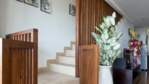 A staircase with wooden railings and a white vase with green plants. - 3 Bedroom Sawah Town House B4 Ocean View   (Tabanan)
